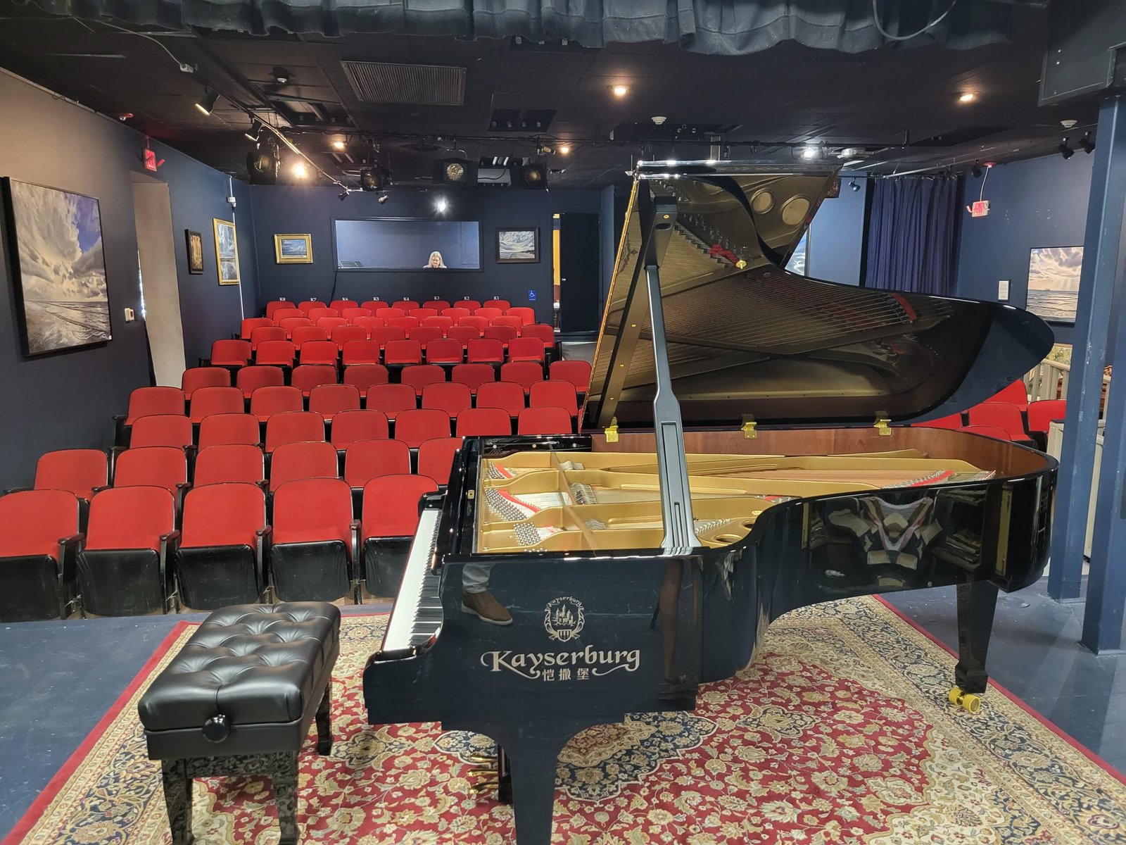 Grand piano on stage looking at sea of red seats